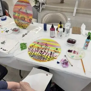 A table with colorful craft supplies. Partially finished artwork on table.